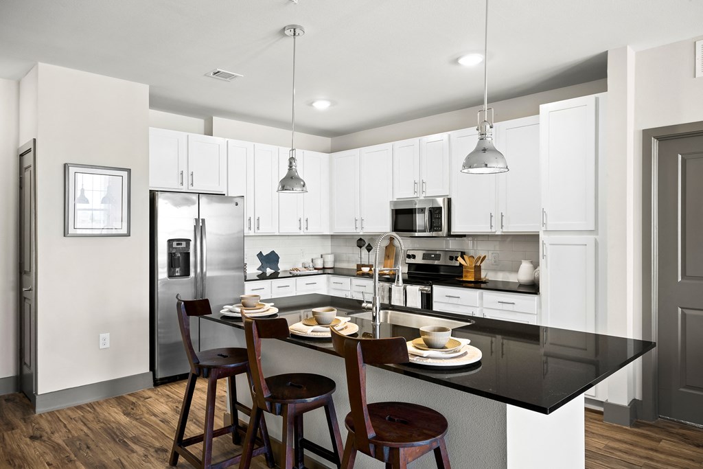 a kitchen with white cabinets and a black counter top