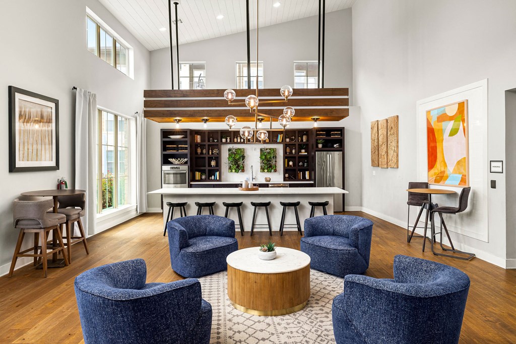 a living room with blue chairs and a kitchen with a bar