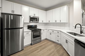A kitchen with white cabinets and a stainless steel refrigerator.