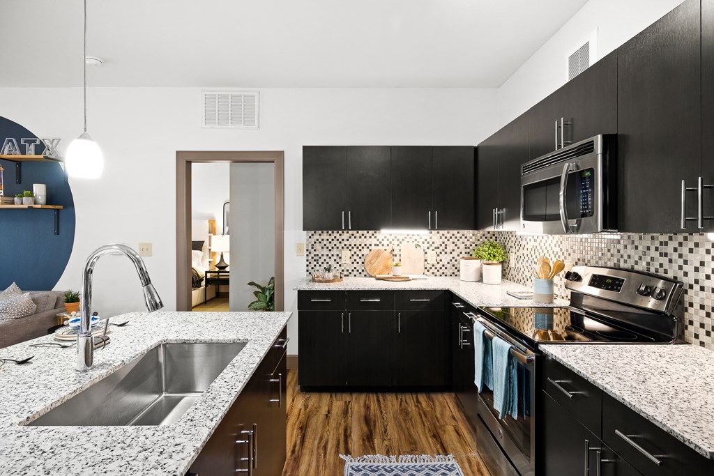 an open kitchen with granite counter tops and black cabinets