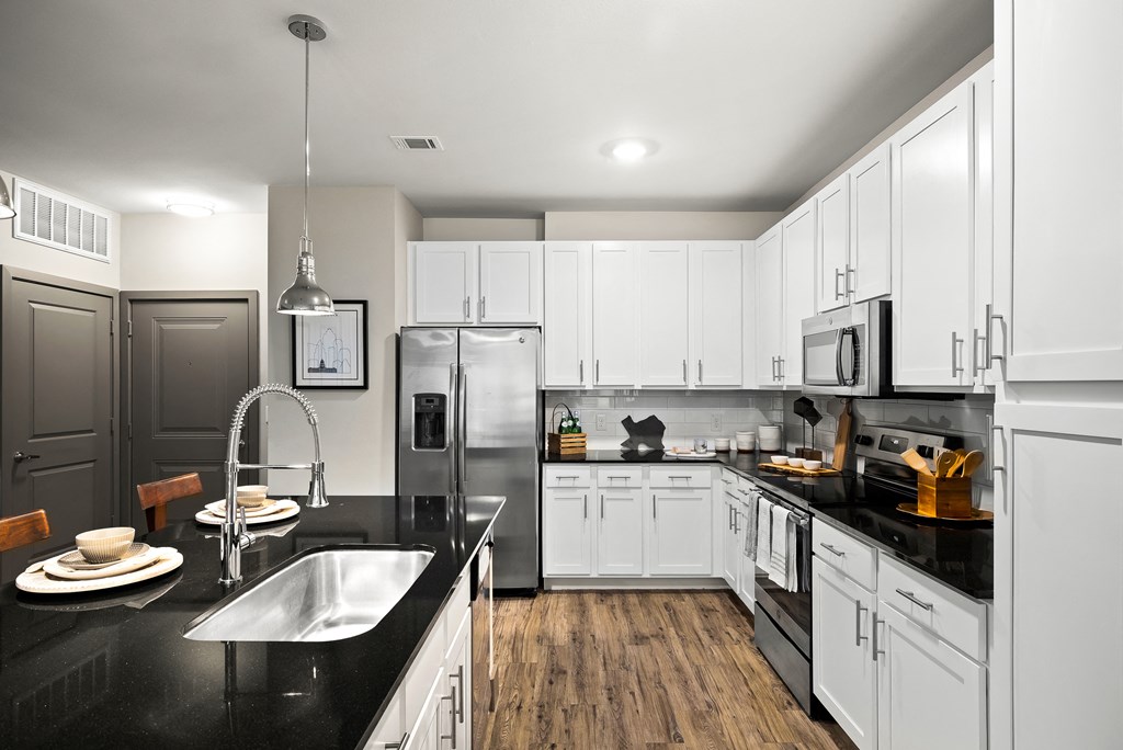 a large kitchen with white cabinets and black counter tops