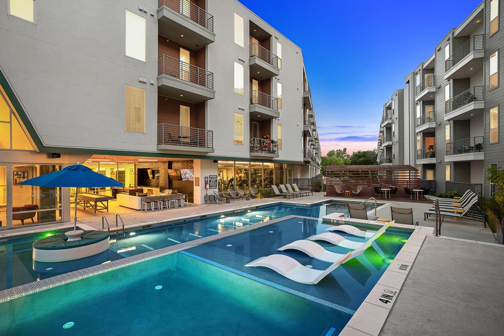 a resort style pool with lounge chairs in front of an apartment building