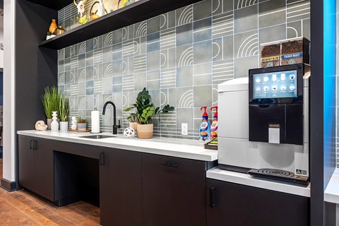 a kitchen with a sink and a coffee maker and a monitor on a counter