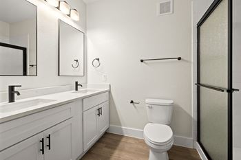 A white toilet sits in a bathroom next to a sink and mirror.