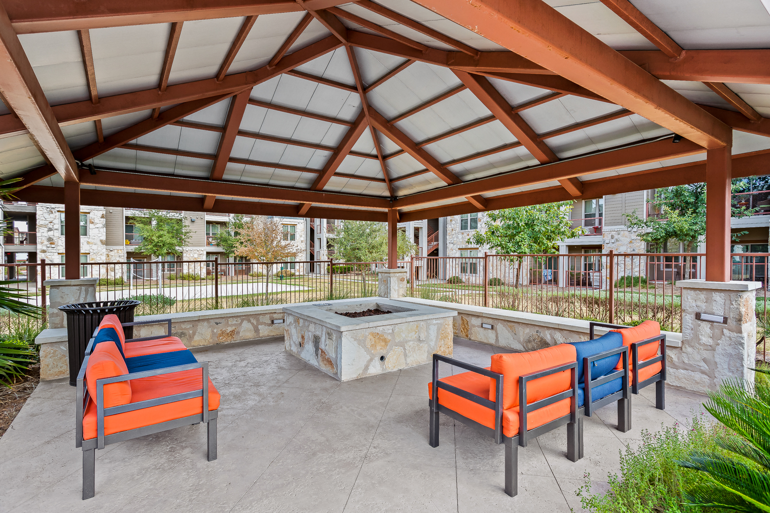 a covered patio with a fire pit and chairs