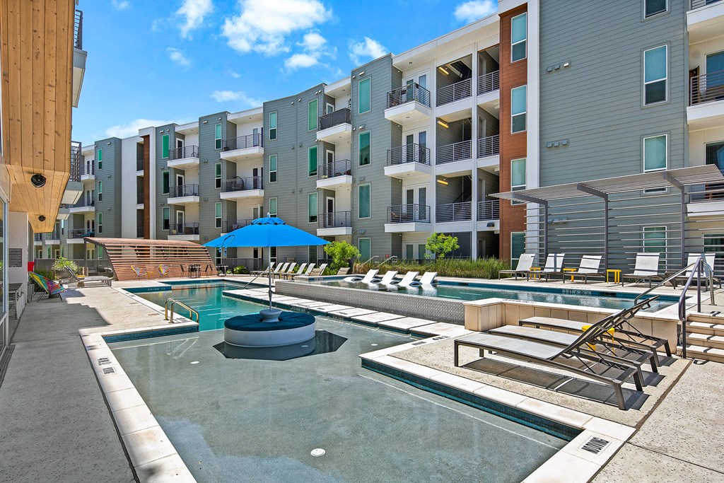an apartment building with a pool and lounge chairs