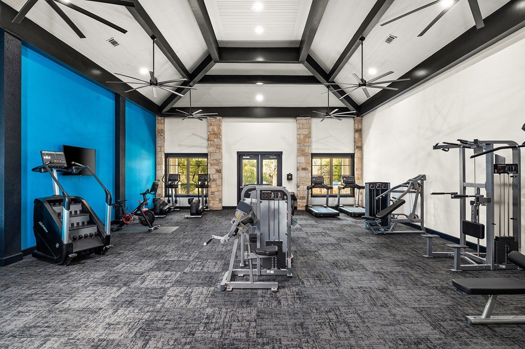 a gym with weights and cardio equipment at the district at highland village apartments