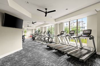 a gym with cardio machines and a tv