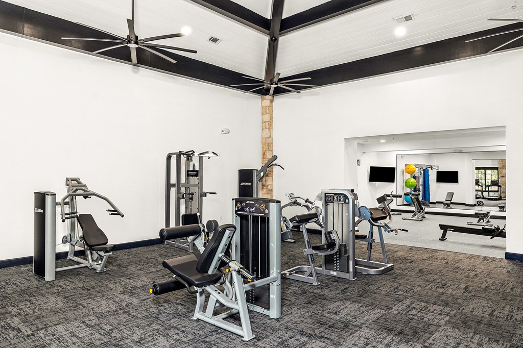 a gym with cardio equipment and weights in a building with white walls