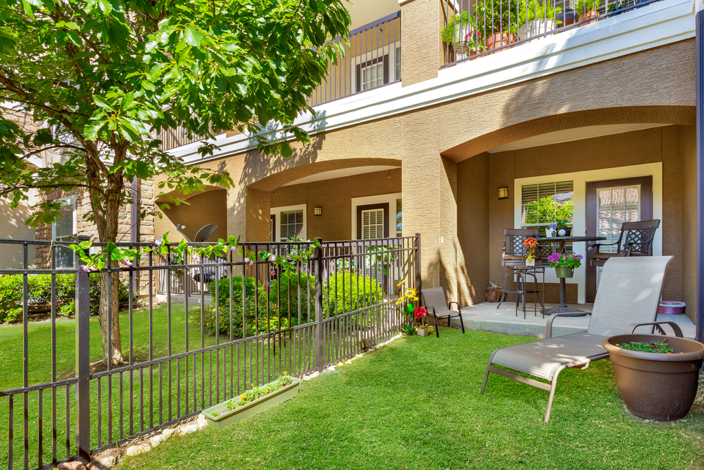 a patio with chairs and a fence in front of a house