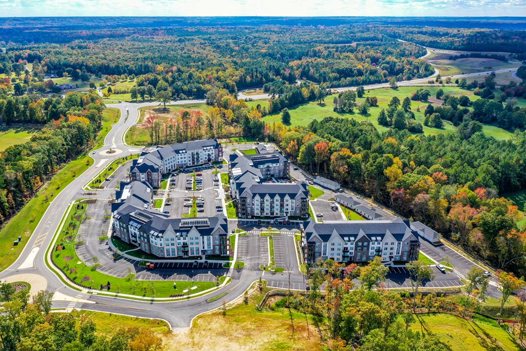 An aerial view of a large building surrounded by a parking lot and trees.