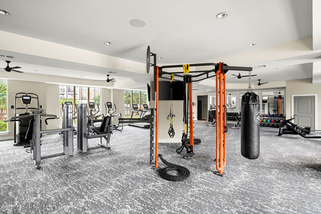 a gym with weights and cardio equipment in a building with windows