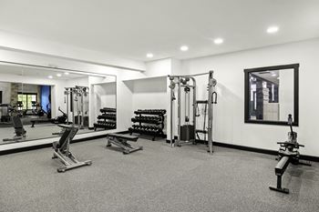 a gym with weights and mirrors and a mirror on the wall