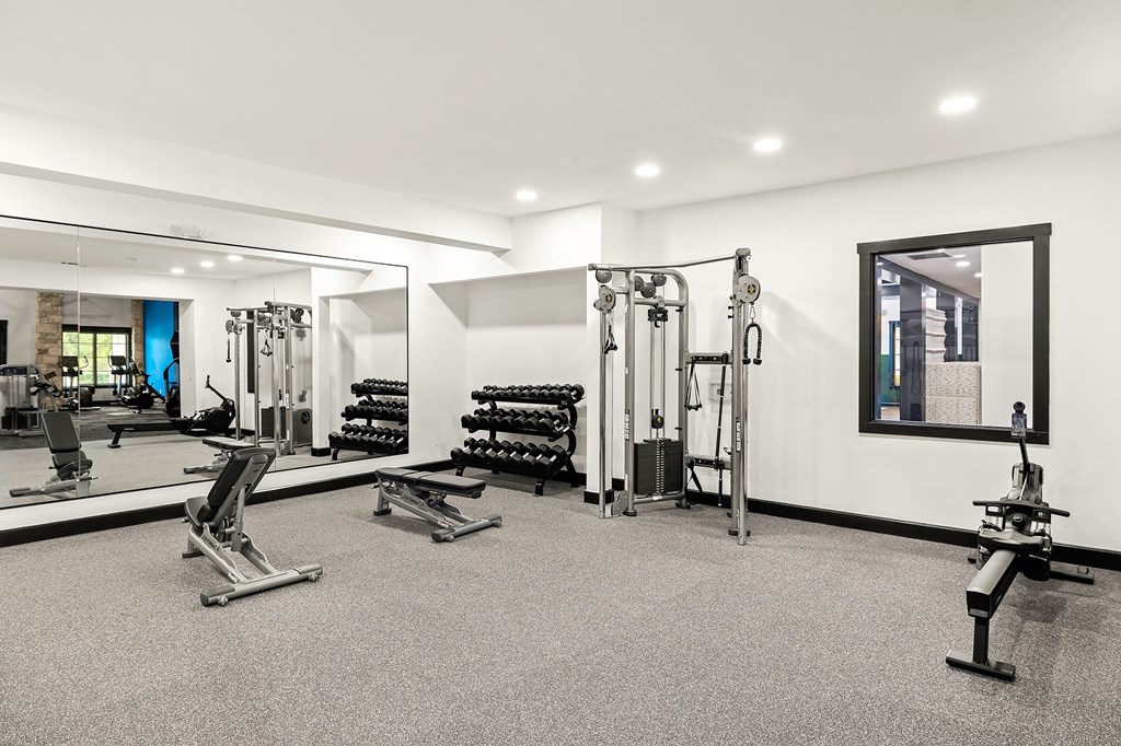 a gym with weights and mirrors and a mirror on the wall