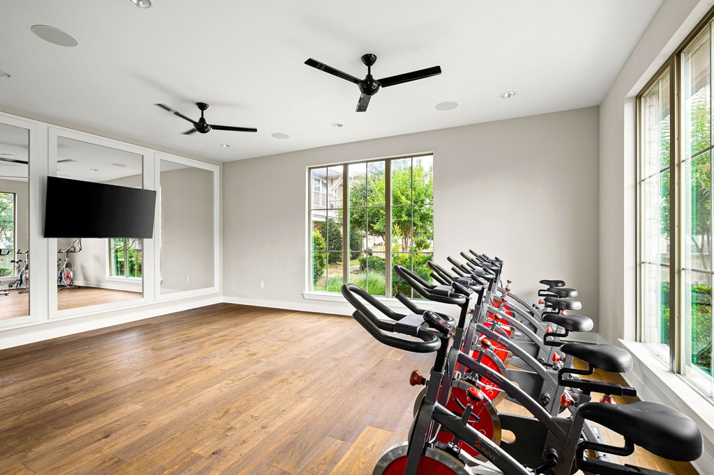 the home gym has a wall of windows and a row of exercise bikes