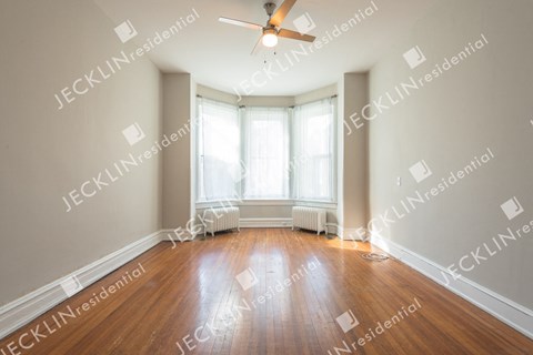 A spacious room with wooden floors and a ceiling fan.