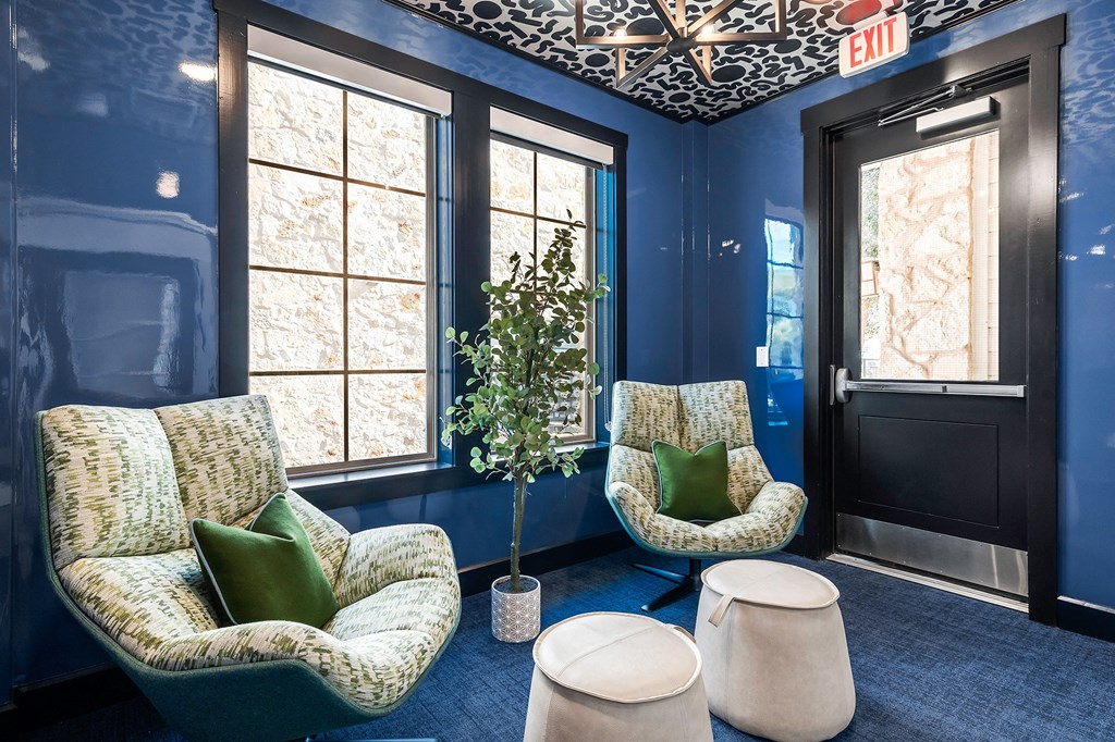 a living room with blue walls and two chairs and a tree
