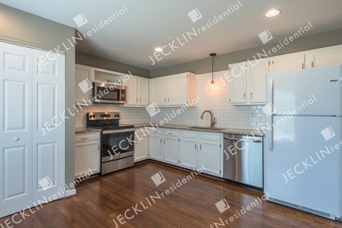 A modern kitchen with white cabinets and stainless steel appliances.