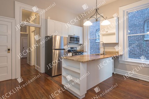 A modern kitchen with a refrigerator, microwave, and stove top oven.