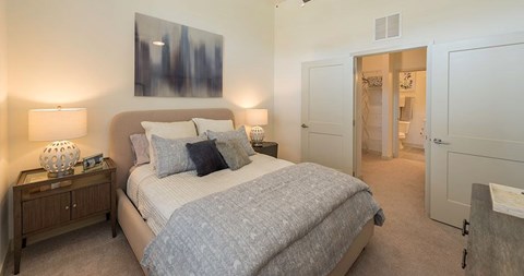 A bedroom with a large bed and a painting on the wall.