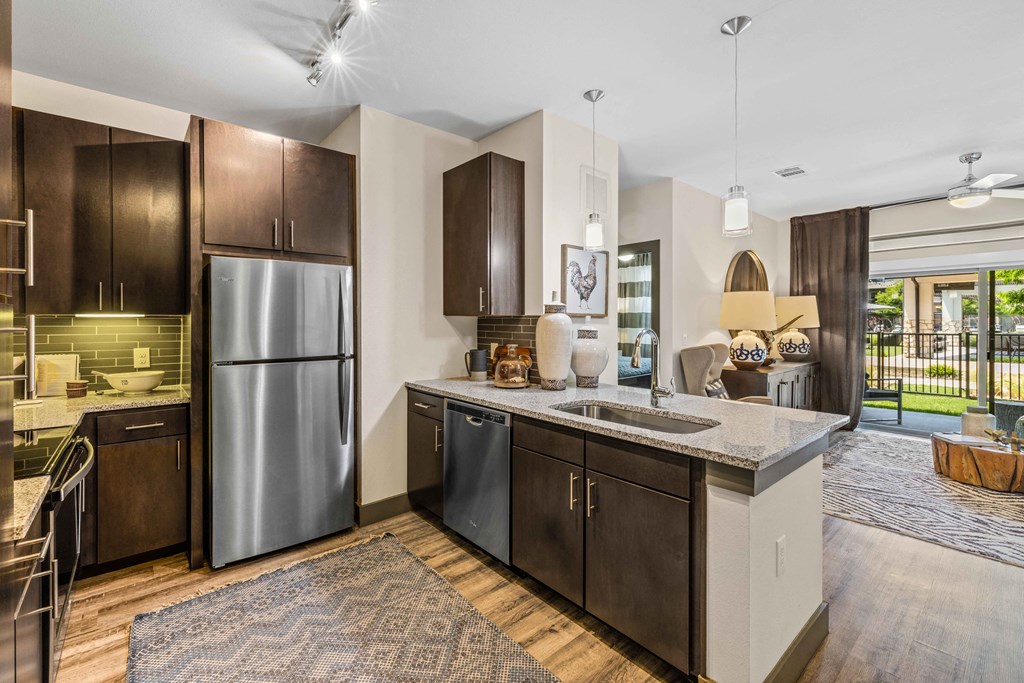 model kitchen overlooking living room. Stainless steel appliances and espresso cabinetry
