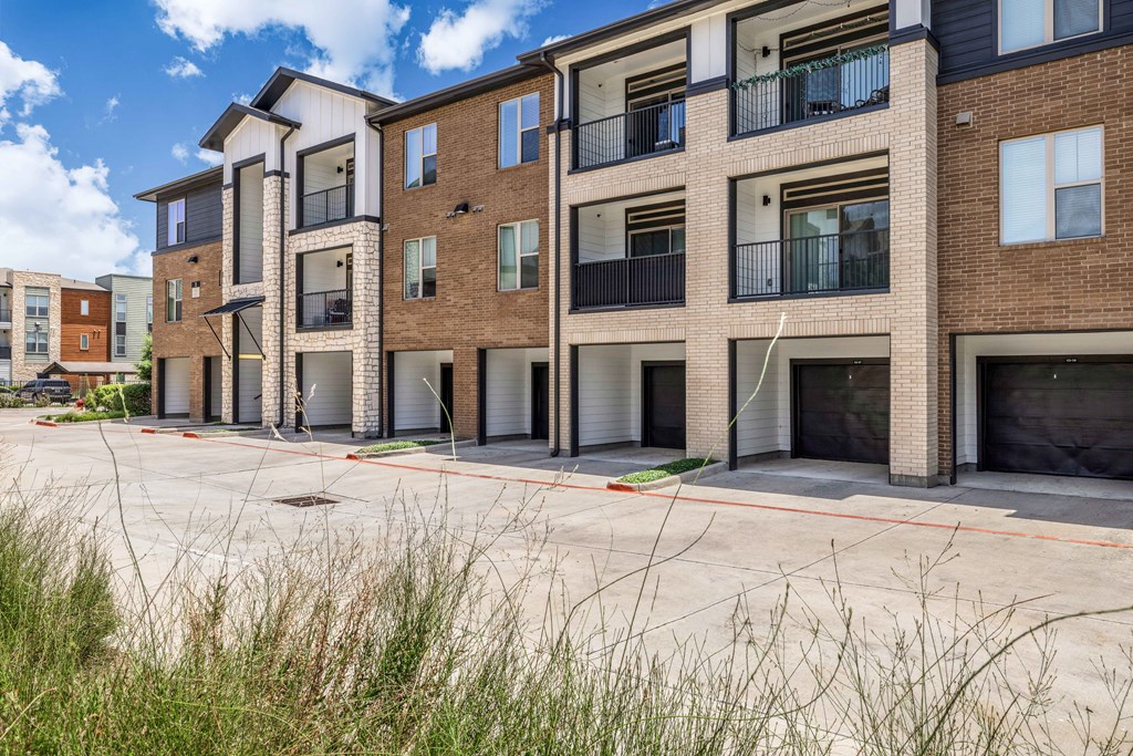 an empty parking lot in front of a brick apartment building