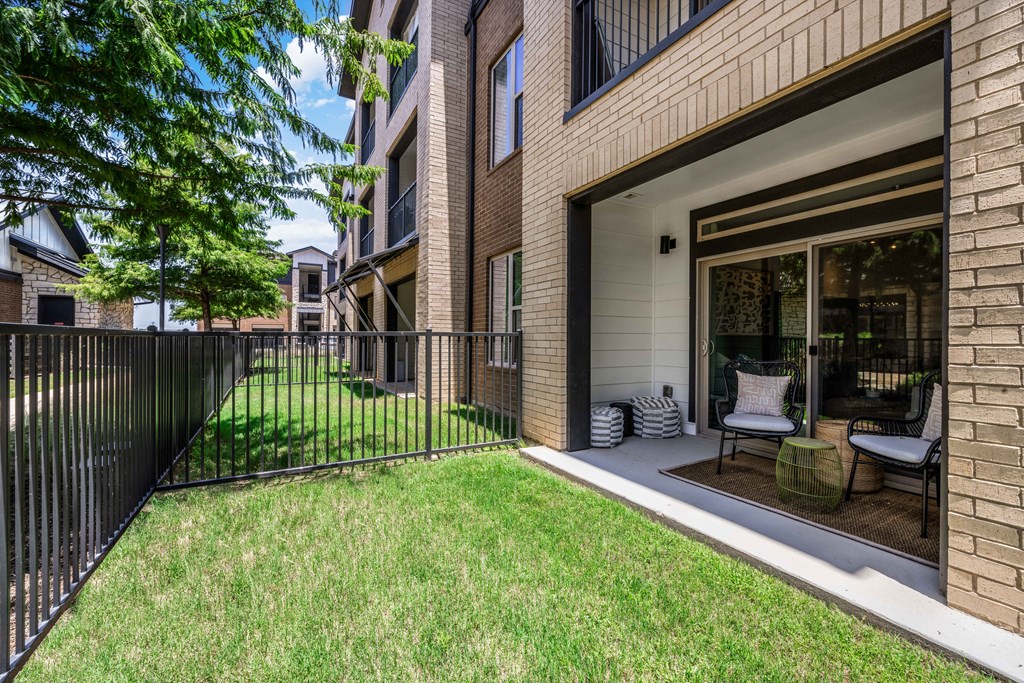 a patio with a fence and a lawn in front of a building