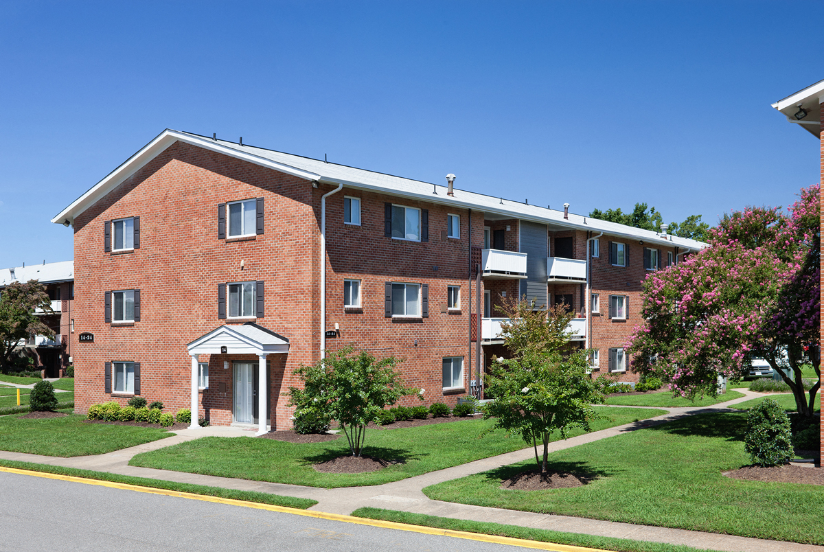 a red brick apartment building with green grass and trees
