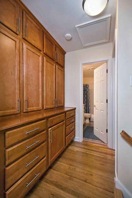 a kitchen with wooden cabinets and a door to a bathroom