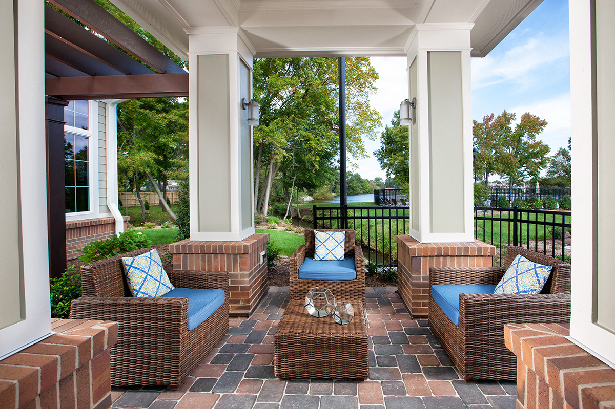 a covered patio with wicker furniture and a view of the water