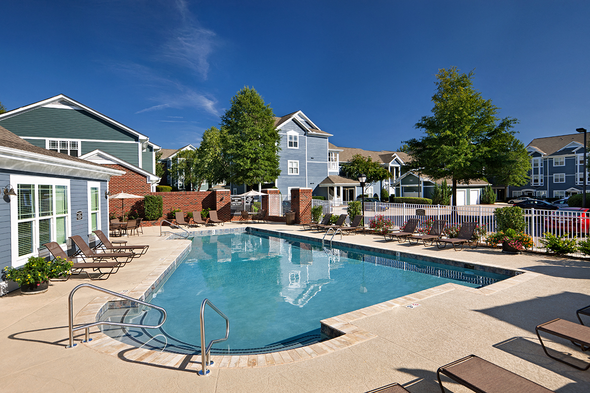 a swimming pool with chairs in front of a building