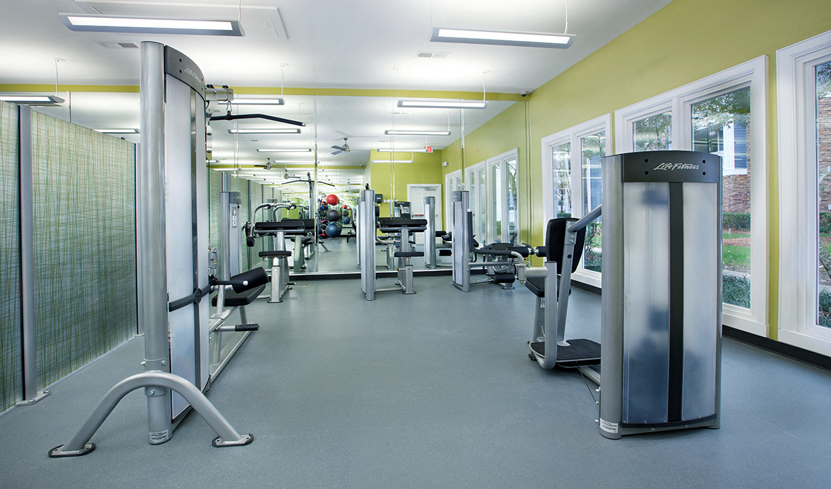 a fitness room with cardio equipment and windows in a building