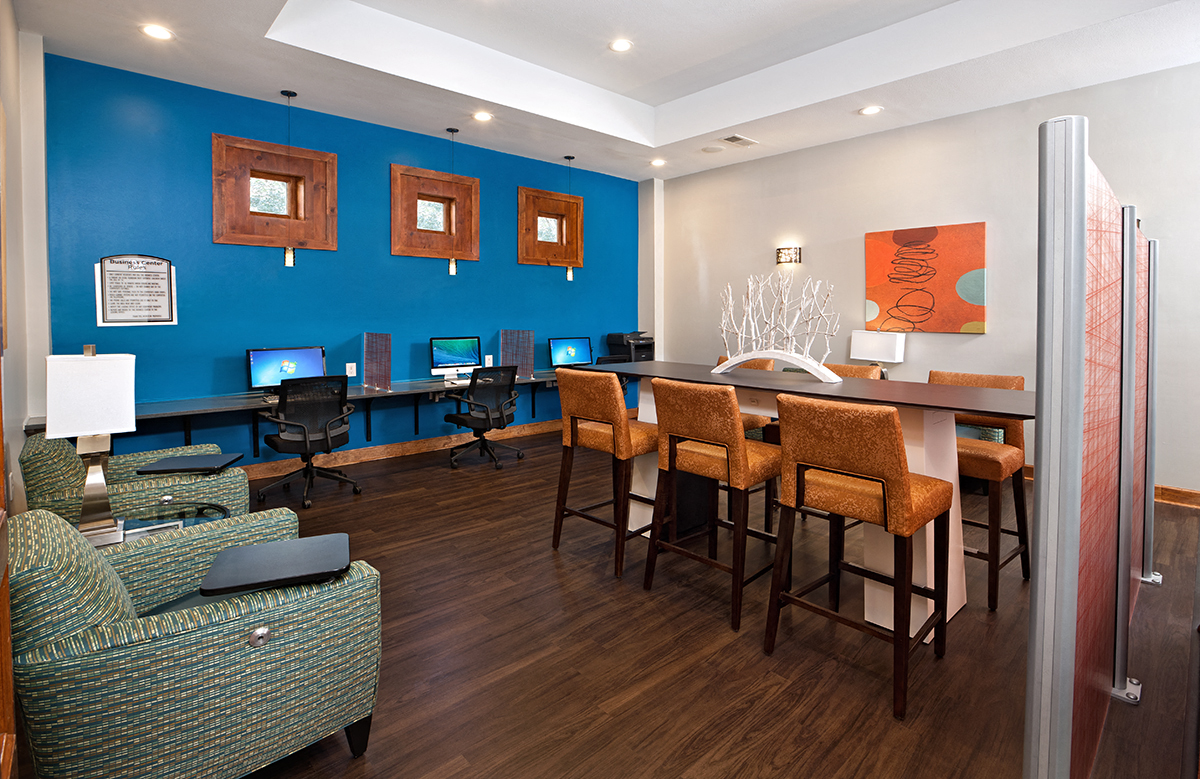 a living room with a table and chairs and a desk with computers