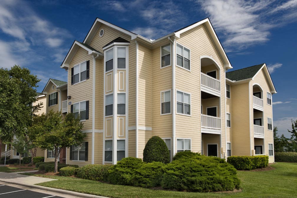 the exterior of an apartment building with trees and shrubs