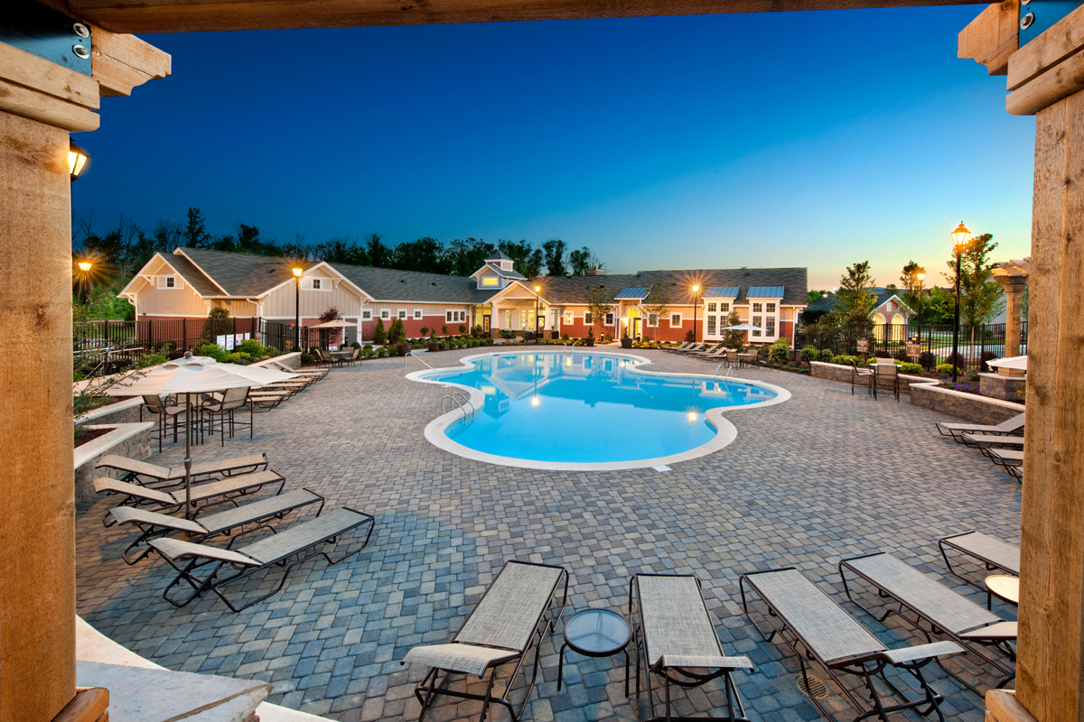 an outdoor pool with lounge chairs and tables at dusk