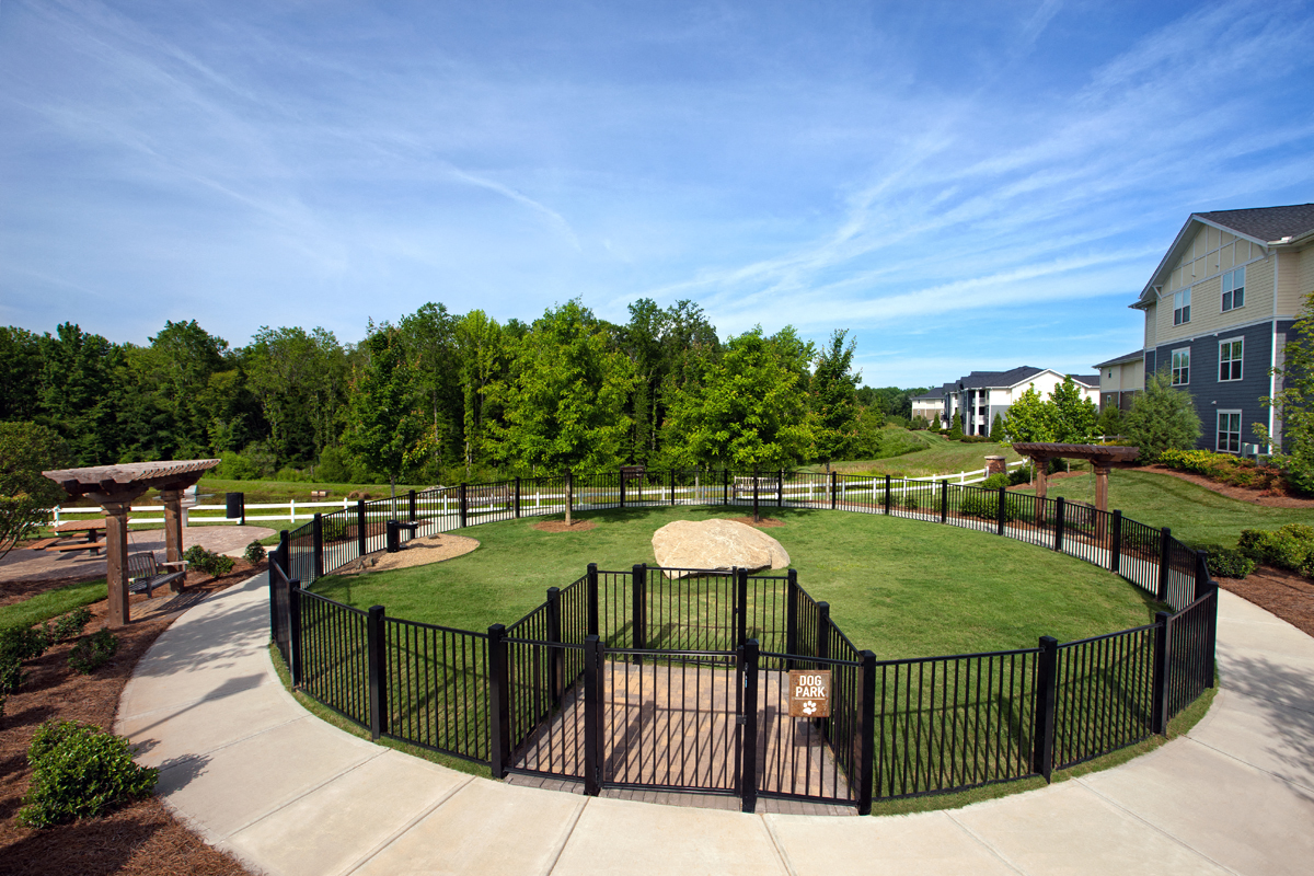 a fenced in dog park in a community with houses