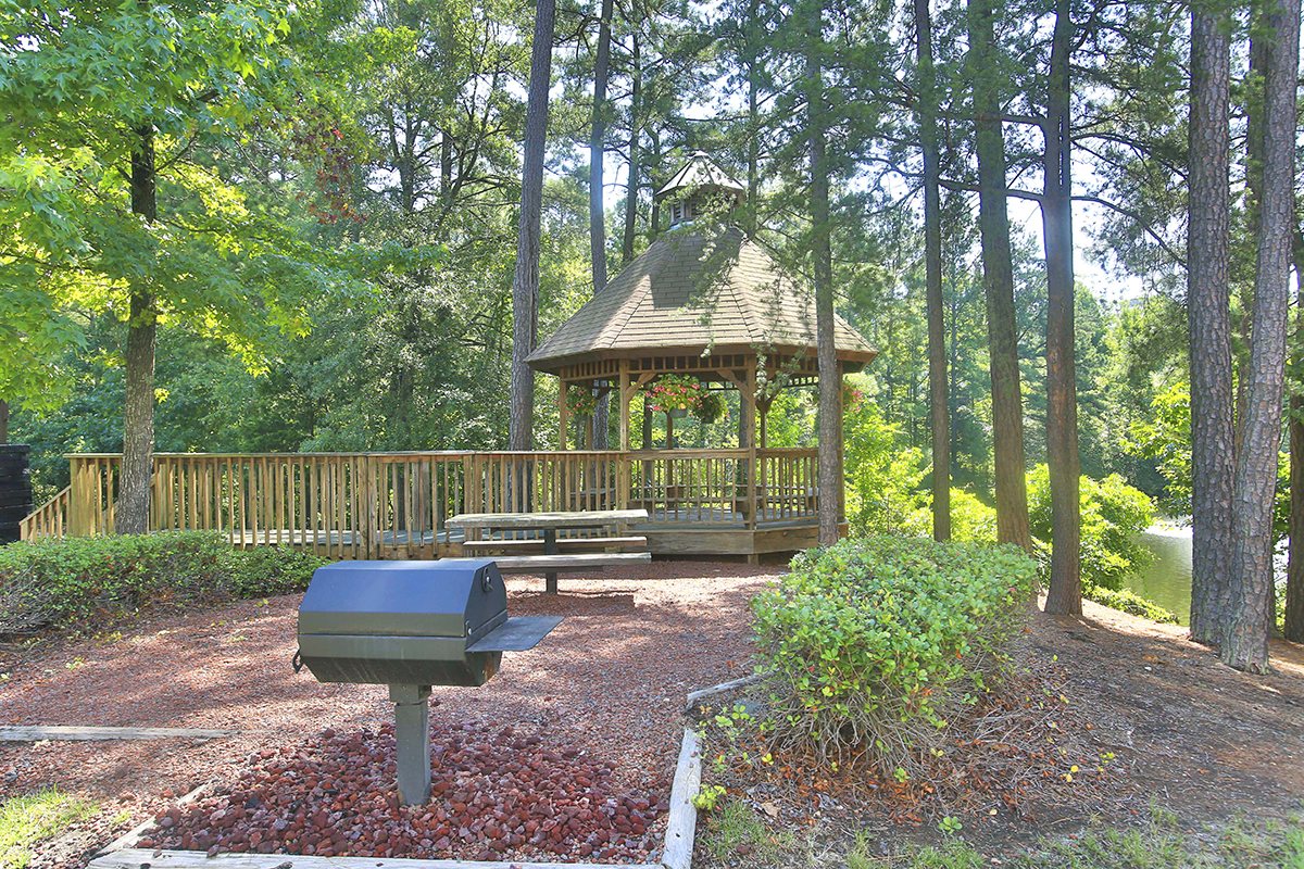 a gazebo in a park with a picnic table and a grill