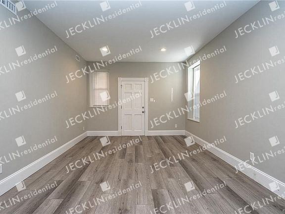 a empty room with a white door and hardwood floors