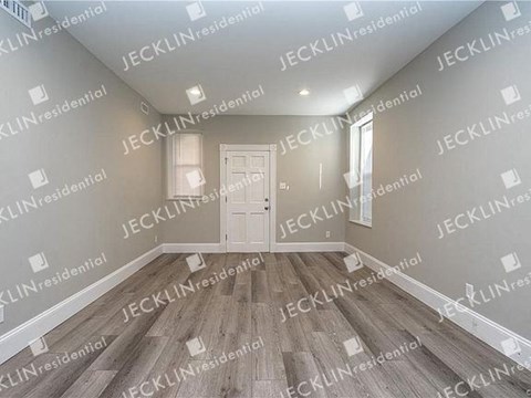 an empty living room with wooden floors and a white door