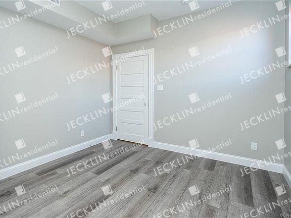 an empty room with a white door and hardwood floors