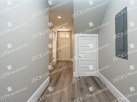 a hallway with a white door and hardwood floors