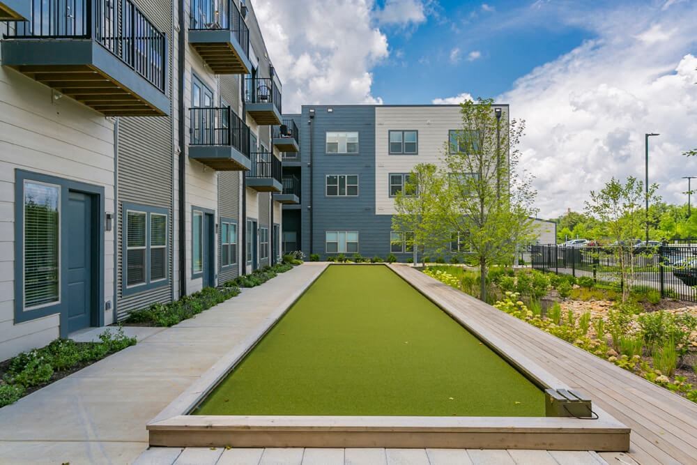 a green carpeted walkway between two apartment buildings