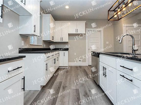 a kitchen with white cabinets and black counter tops