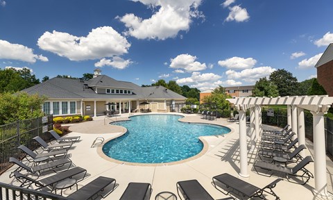 A large outdoor swimming pool surrounded by sun loungers and a covered seating area.