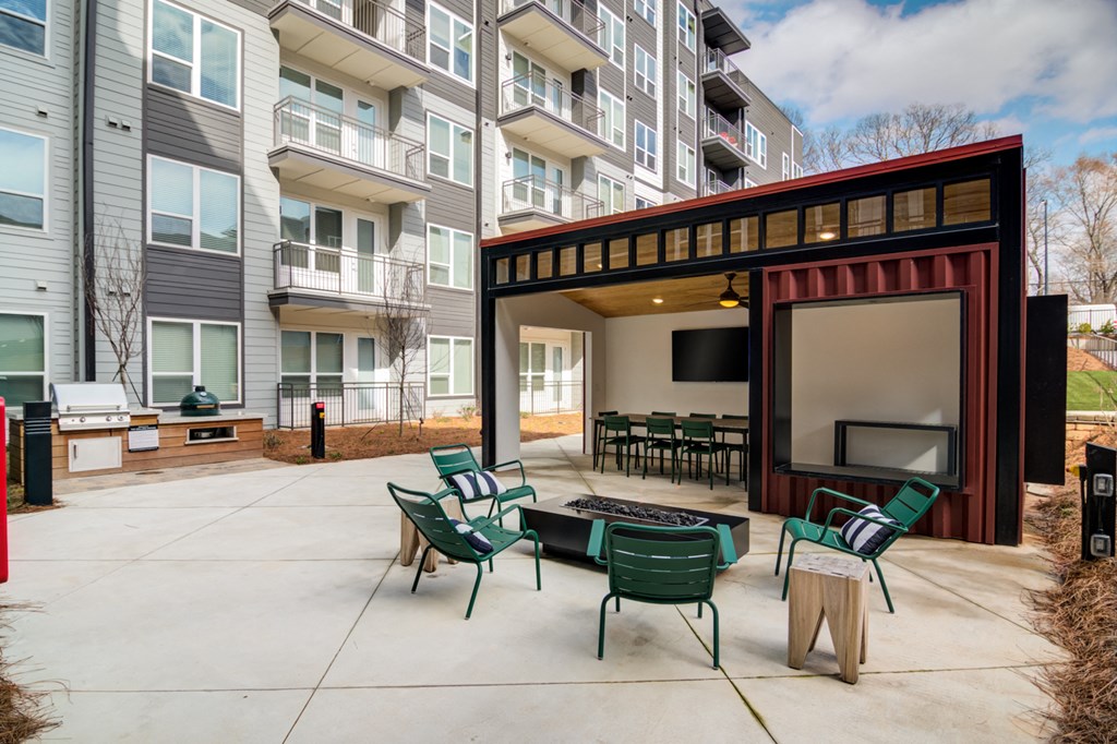 a patio with chairs and a fire pit in front of an apartment building