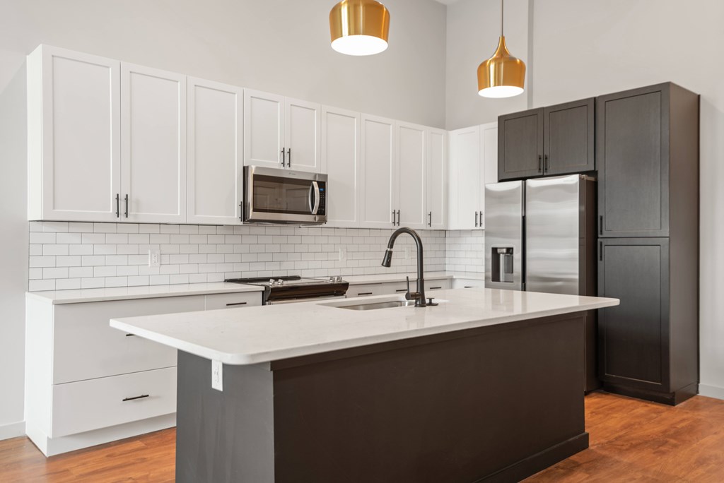 A kitchen with white cabinets and a black refrigerator.