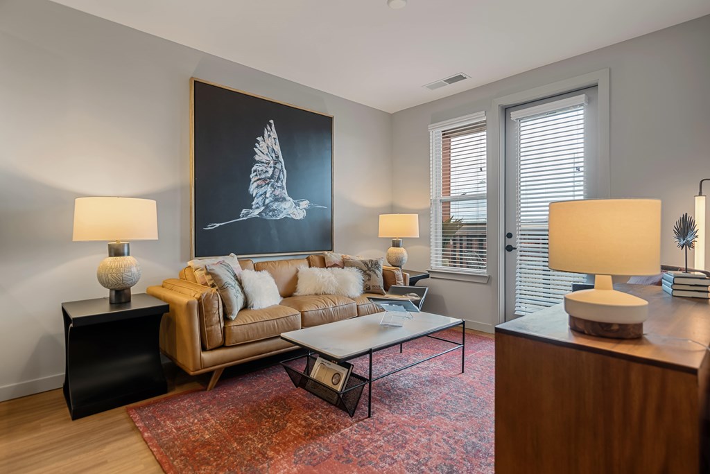 A living room with a couch, a coffee table, and a large painting of a bird.