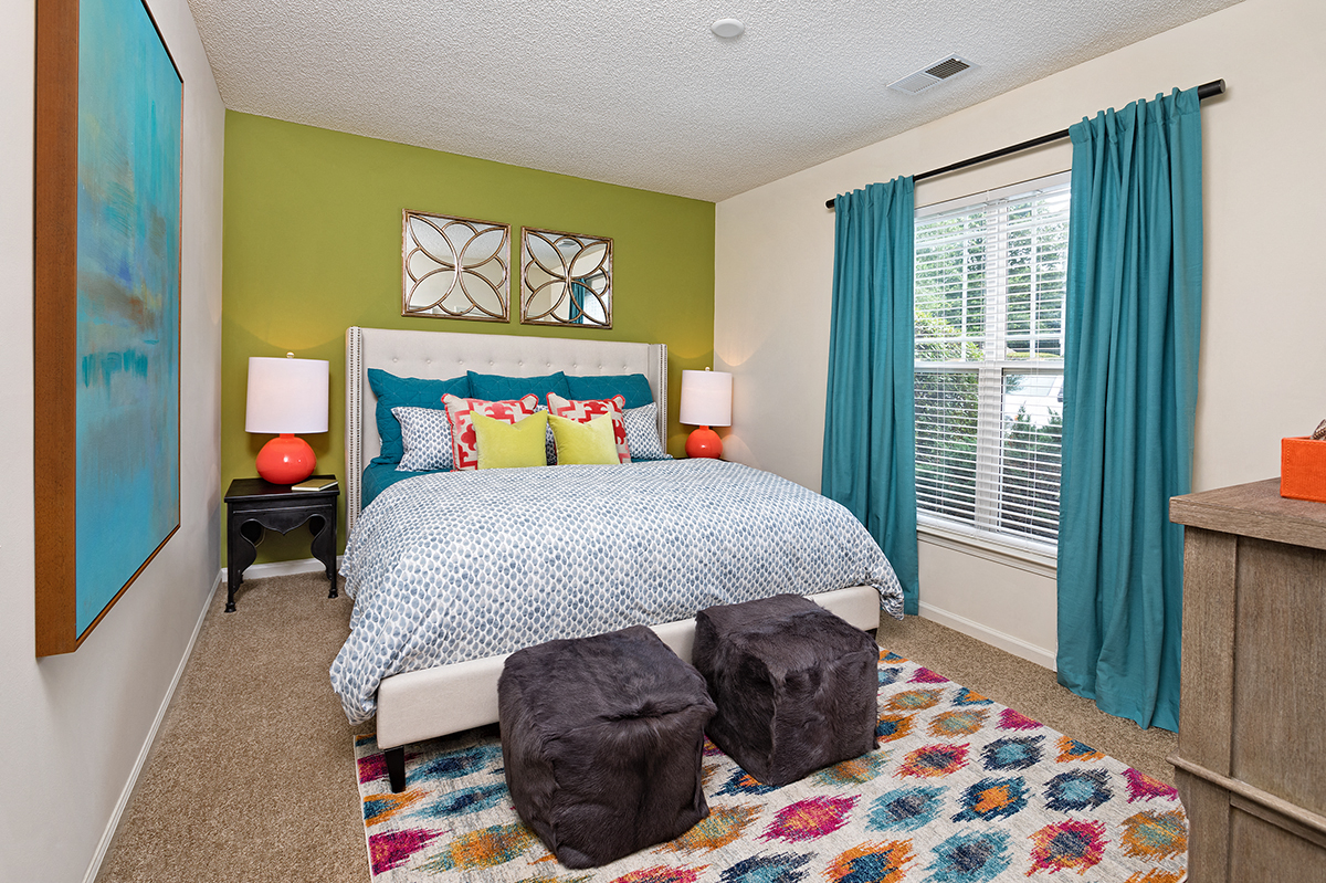 a bedroom with green walls and a bed with blue and yellow pillows