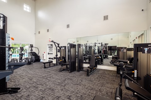 a gym with cardio equipment and mirrors on the wall
