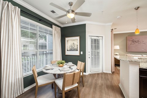 A dining room with a table set for four and a ceiling fan.